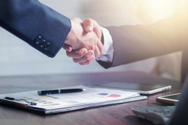 Professional handshake agreement over business charts in an office setting.