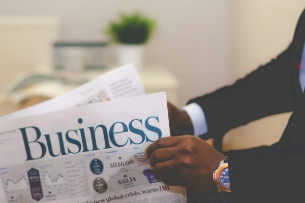 Close-up of a businessman reading a newspaper indoors, focusing on business headlines.