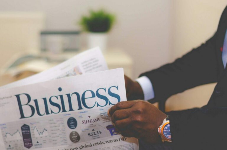 Close-up of a businessman reading a newspaper indoors, focusing on business headlines.